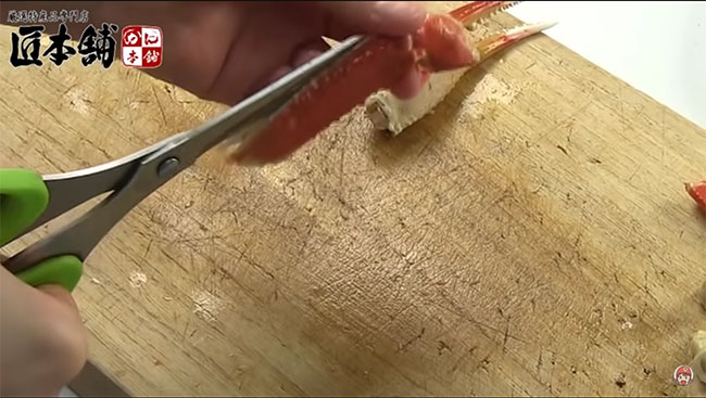 カニの爪の殻を切り進めている